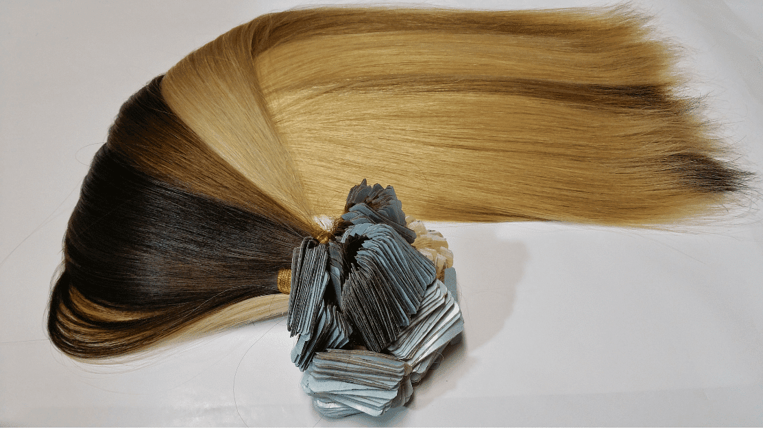Blonde and brown hair extensions with metallic clips arranged on a white background.