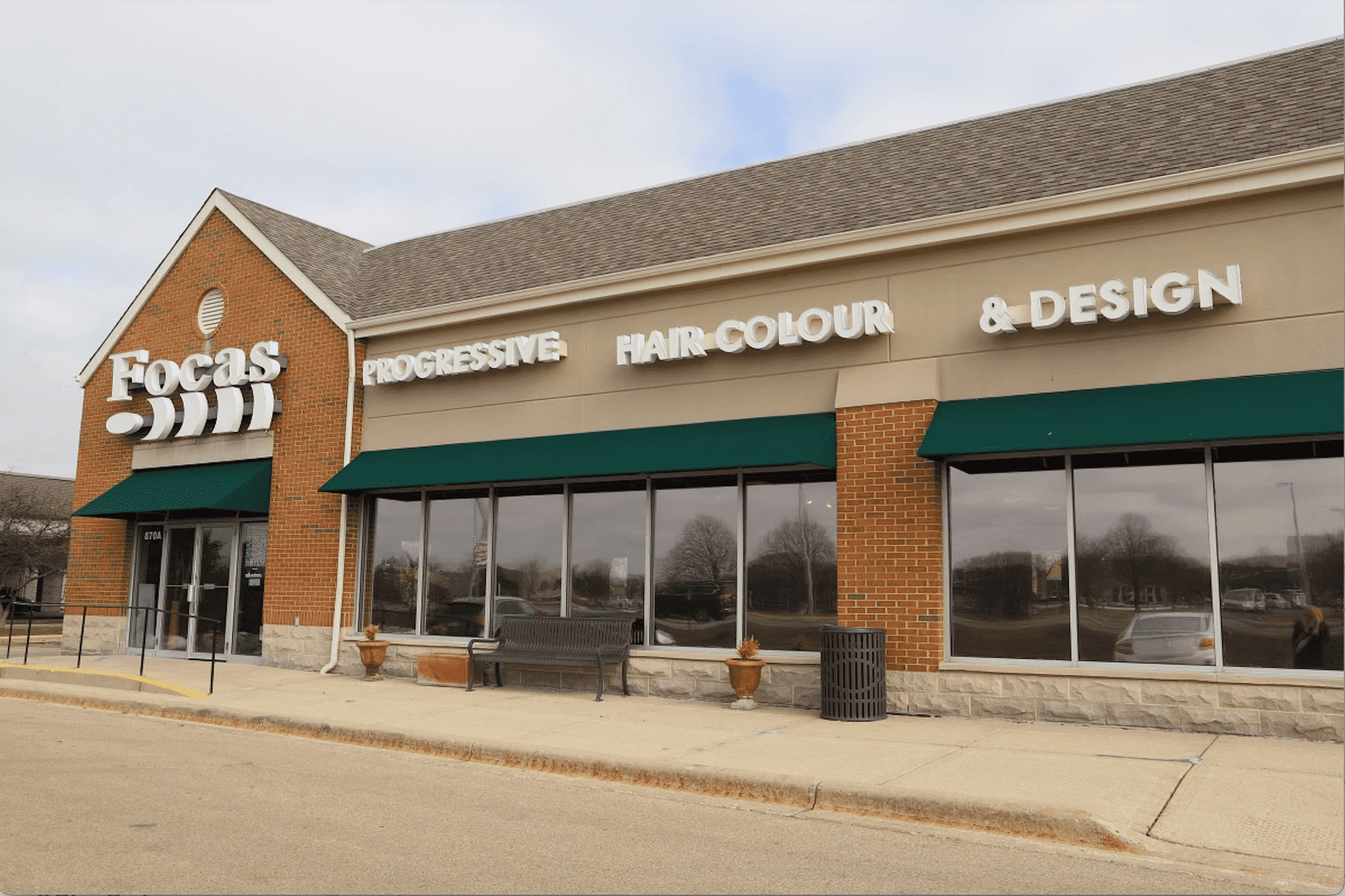 Exterior of a strip mall with various storefronts, including a salon.