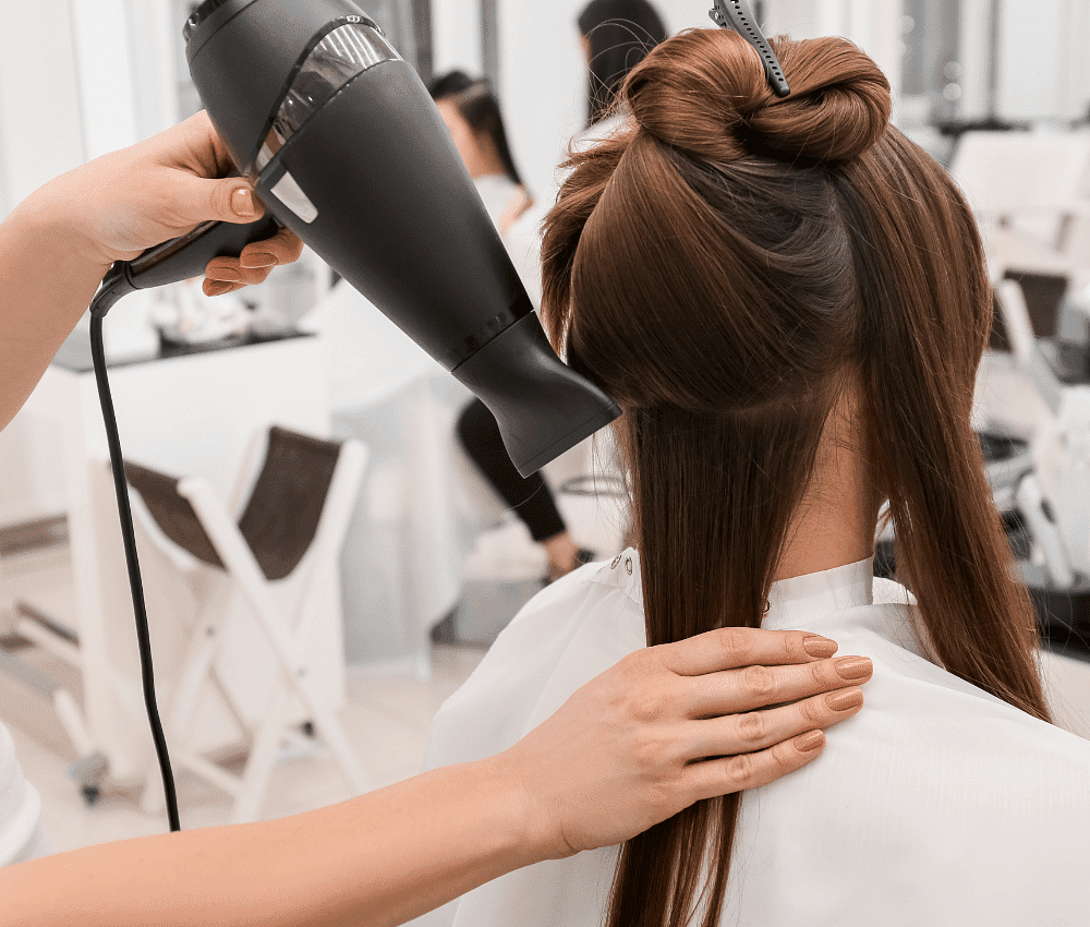 Hairdresser drying a client's hair in a salon.